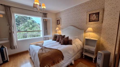 a bedroom with a large bed with a window at Pousada Atalaia Premium in Campos do Jordão