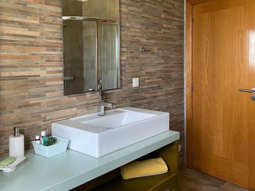 een badkamer met een witte wastafel en een spiegel bij Cantinho do Minho - Ponte de Lima in Ponte de Lima