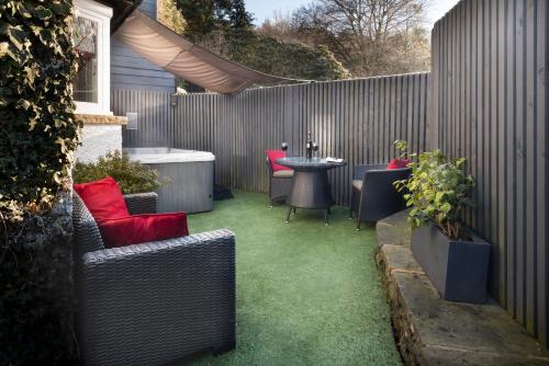 a patio with a table and chairs and a fence at Aphrodites Group - Luxury Hot Tub Suites in Central Lake District! in Bowness-on-Windermere