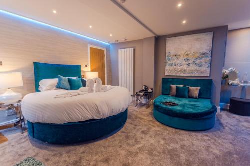 a large bedroom with a large bed and a chair at Aphrodites Group - Luxury Hot Tub Suites in Central Lake District! in Bowness-on-Windermere