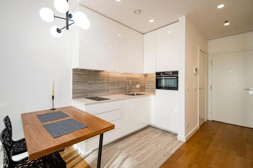 a kitchen with white cabinets and a wooden table at West 21 Tower in Fontana