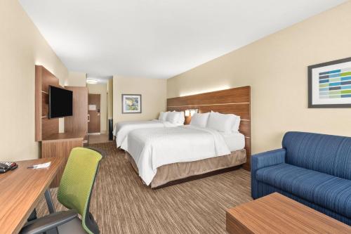 a hotel room with a large bed and a blue couch at Holiday Inn Express Corning by IHG in Corning