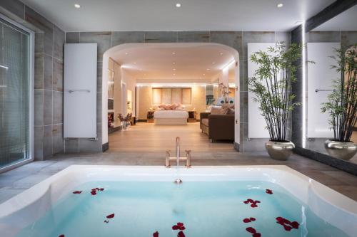 a large bath tub in a room with a bedroom at Aphrodites Group - Luxury Hot Tub Suites in Central Lake District! in Bowness-on-Windermere