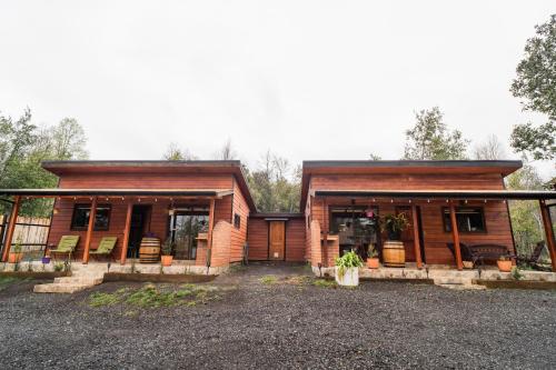 a log home with a large front porch at Pucón Rec-Lodge Cabaña Loro Tricahue in Pucón