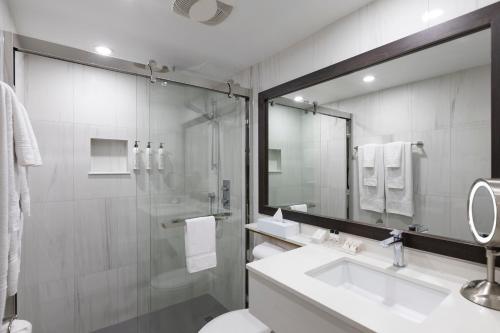 a bathroom with a sink and a shower and a mirror at Le Nouvel Hotel in Montréal