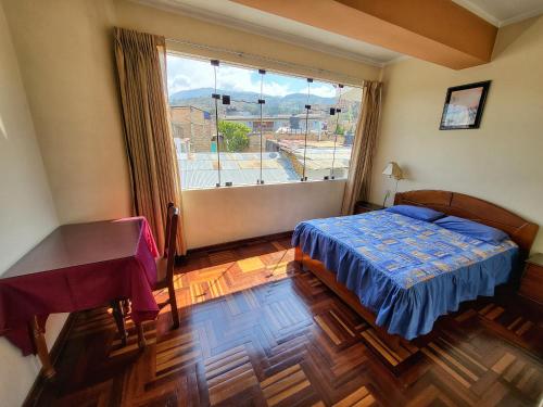 a bedroom with a bed and a desk and a window at D'Cardenas Hotel in Cajamarca