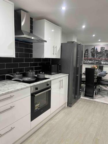 a kitchen with white cabinets and a black refrigerator at NEW Modern 5 Bedroom House - City Centre - Parking in Cardiff