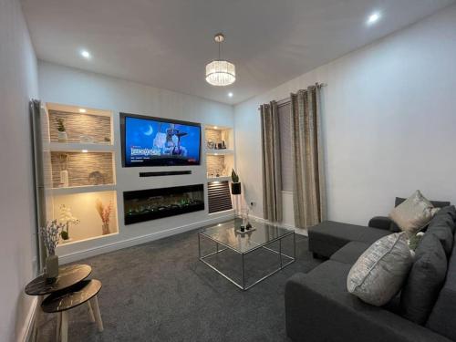 a living room with a couch and a flat screen tv at NEW Modern 5 Bedroom House - City Centre - Parking in Cardiff