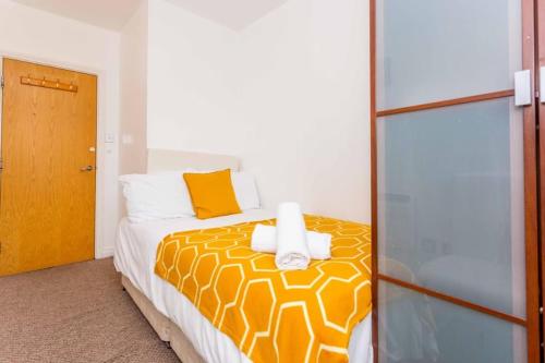 a bedroom with a bed with yellow and white sheets at Midas Lodge in Newcastle upon Tyne
