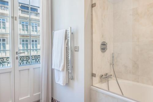 a bathroom with a tub and a shower with a window at InterContinental Porto - Palacio das Cardosas by IHG in Porto