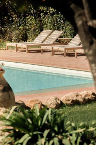 a swimming pool with two chairs and some rocks at Il Mulino di Nonna Sà - Prestige Private Villa in Pietrasanta