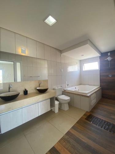 a bathroom with two sinks and a tub and a toilet at Refúgio da Praia Aracaju in Aracaju