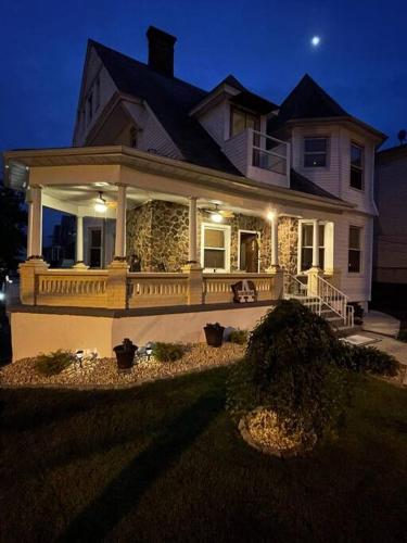a large white house with a porch at night at The Pearl-Lovely Victorian Home with Bed and Breakfast Energy in West Bergen
