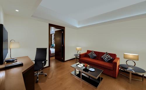 a living room with a red couch and a table at The Fern Kadamba Hotel And Spa in Old Goa