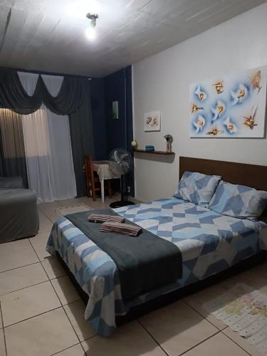 a bedroom with a blue and white bed and a chair at Pousada Paradise in Rio Grande
