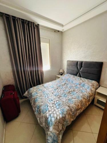 1 dormitorio con 1 cama y 1 maleta roja en appartement sublime, en Oulad Hamida