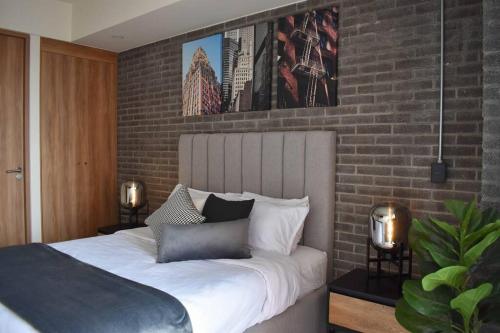 a bedroom with a bed with a brick wall at Nuevo Depa con increible vista en YU Country 1804 in Guadalajara
