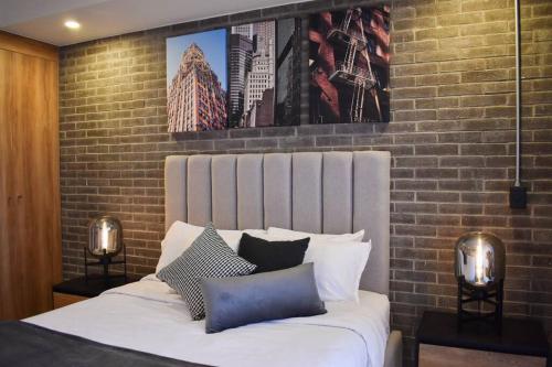a bedroom with a white bed with a brick wall at Nuevo Depa con increible vista en YU Country 1804 in Guadalajara