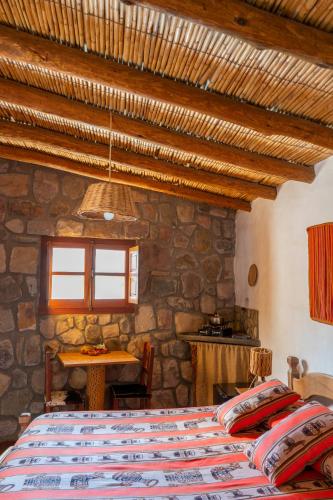 a bedroom with a bed and a stone wall at Hosteria La Morada in Tilcara