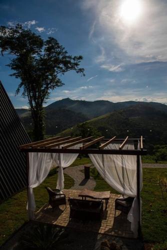 a pergola with a table and chairs under it at Refúgio dos Alpes cabana in Teresópolis