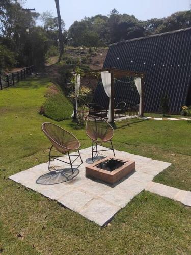 two chairs and a fire pit in the grass at Refúgio dos Alpes cabana in Teresópolis