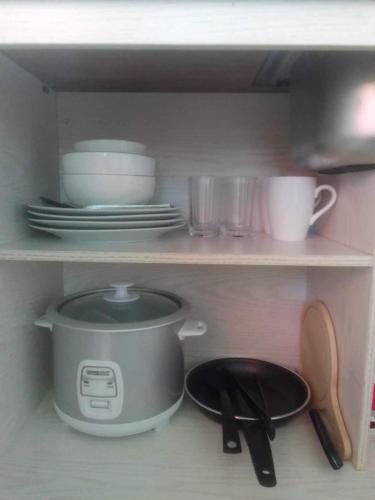 a kitchen shelf with a pot and plates and utensils at Bay Ellie B and B tiny home in Asturias