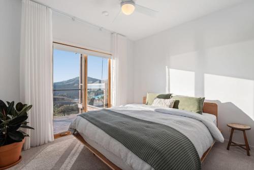 a white bedroom with a bed and a large window at The Good House in Kiewa