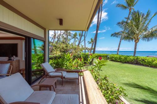 a patio with a table and chairs and the ocean at Puunoa Beach Estates 103 in Lahaina
