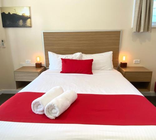 a bedroom with a red and white bed with towels on it at Jervis Bay Mariners in Huskisson