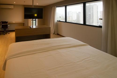 a bedroom with a bed and a desk and a window at Luxuoso Flat No Hotel Radisson EXCELENTE LOCALIZAÇÃO in Belém