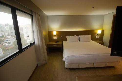 a hotel room with a bed and a large window at Luxuoso Flat No Hotel Radisson EXCELENTE LOCALIZAÇÃO in Belém
