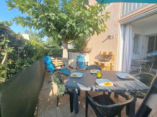 une table et des chaises sur une terrasse avec un arbre dans l'établissement Apt RDC avec accès direct plage, grande terrasse, cuisine équipée, PARKING - FR-1-326-837, à Marseillan