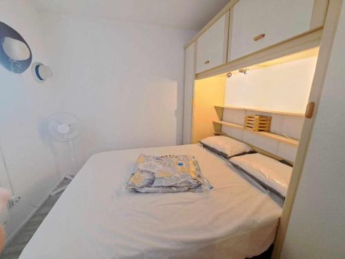 - une petite chambre avec un lit et un couvre-lit blanc dans l'établissement Apt RDC avec accès direct plage, grande terrasse, cuisine équipée, PARKING - FR-1-326-837, à Marseillan