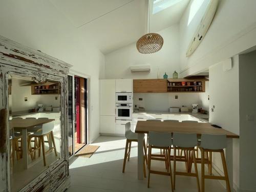 une cuisine avec une table en bois et quelques chaises dans l'établissement Villa rénovée avec accès plage, clim, WiFi, parking - FR-1-413-248, à Capbreton