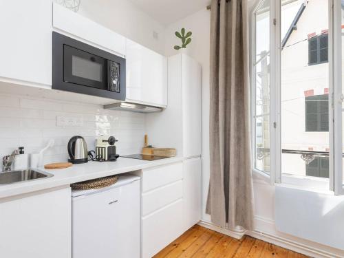 une cuisine blanche avec un évier et une fenêtre dans l'établissement Charmant studio à deux pas de la plage à Cabourg - FR-1-788-32, à Cabourg