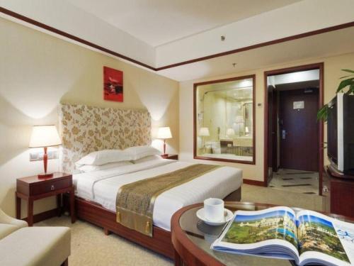 a bedroom with a bed and a table with a book at Starmoon Hotel in Beijing