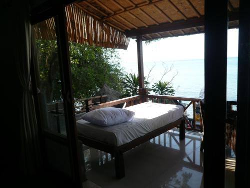 a bed on a balcony with a view of the ocean at Wawa Wewe II Villas in Amed