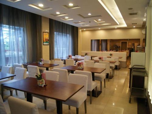 a dining room with tables and white chairs at Magnotel Shanghai Maglev Station in Shanghai