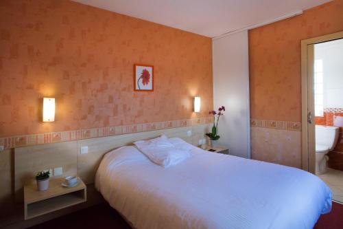 a bedroom with a large white bed and a bathroom at Logis Le Commerce in Guichen