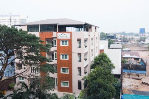 a tall white and red building with trees in front of it at At Home at Udon in Udon Thani