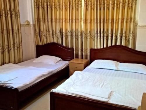 two beds in a bedroom with curtains at Quang Sang Hotel Can Tho in Can Tho