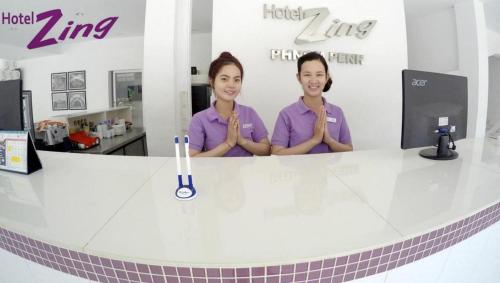 two women in purple shirts standing behind a counter at Hotel Zing Phnom Penh in Phnom Penh
