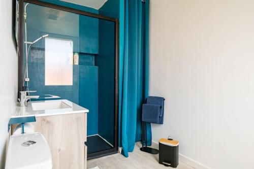 La salle de bains est pourvue d'un lavabo, de toilettes et de murs bleus. dans l'établissement Les Appart'Hôtels Du Calaisis - 102 Shadow, à Calais