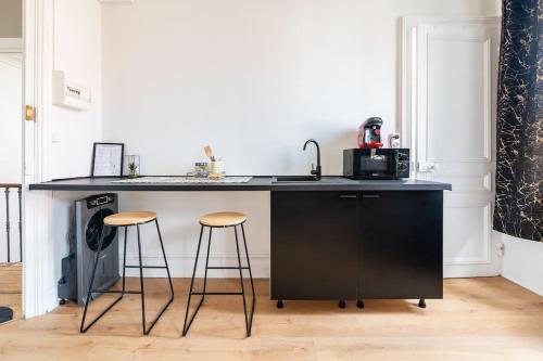 une cuisine avec un comptoir noir et deux tabourets de bar dans l'établissement Les Appart'Hôtels Du Calaisis - 102 Shadow, à Calais