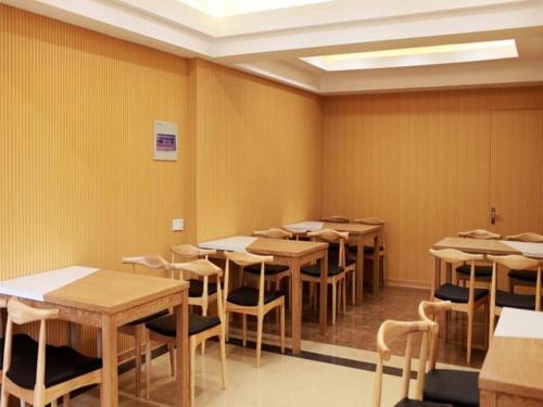 a row of tables and chairs in a room with yellow walls at GreenTree Inn Nanjing Forestry University National Exhibition Center Express Hotel in Nanjing