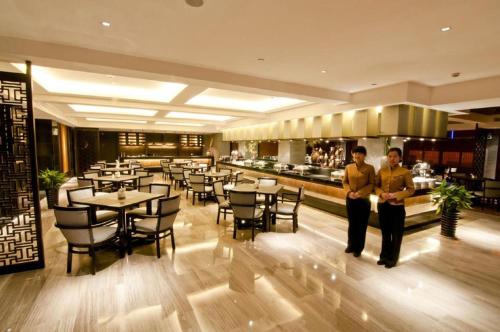 two men standing in a restaurant with tables and chairs at Dajiuhua Hotel in Chizhou