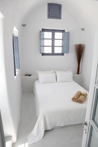 a white bedroom with a white bed and a window at Santoniro Villa in Fira