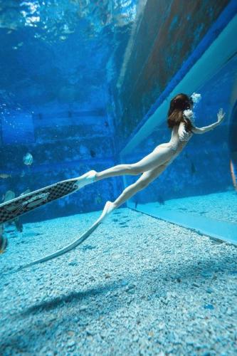 a woman swimming in an aquarium with a hose at Beluga Sanya Discovery Ocean World in Shangsimacun