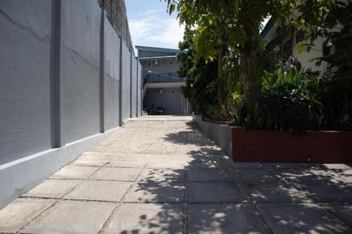 an empty sidewalk next to a building with trees at SPOT ON 2063 Bethania Residence in Kupang