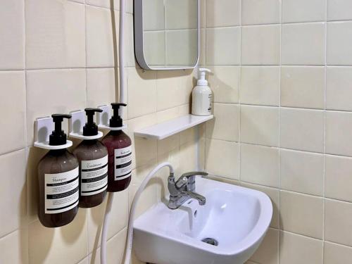 a bathroom with a sink and two bottles on the wall at GuRoom House Seoul in Seoul